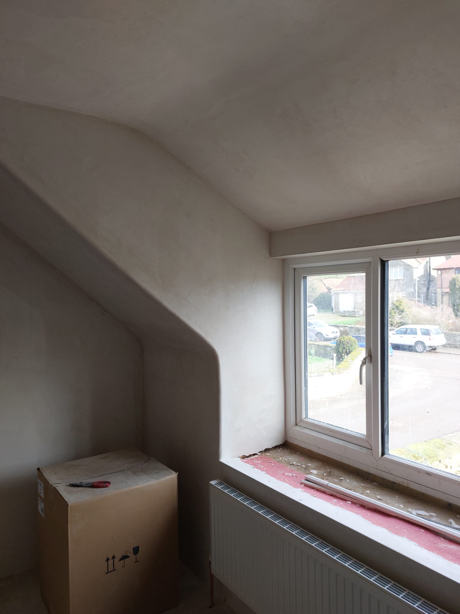 A dormer window bay in a loft room, plastered smooth with a curved return