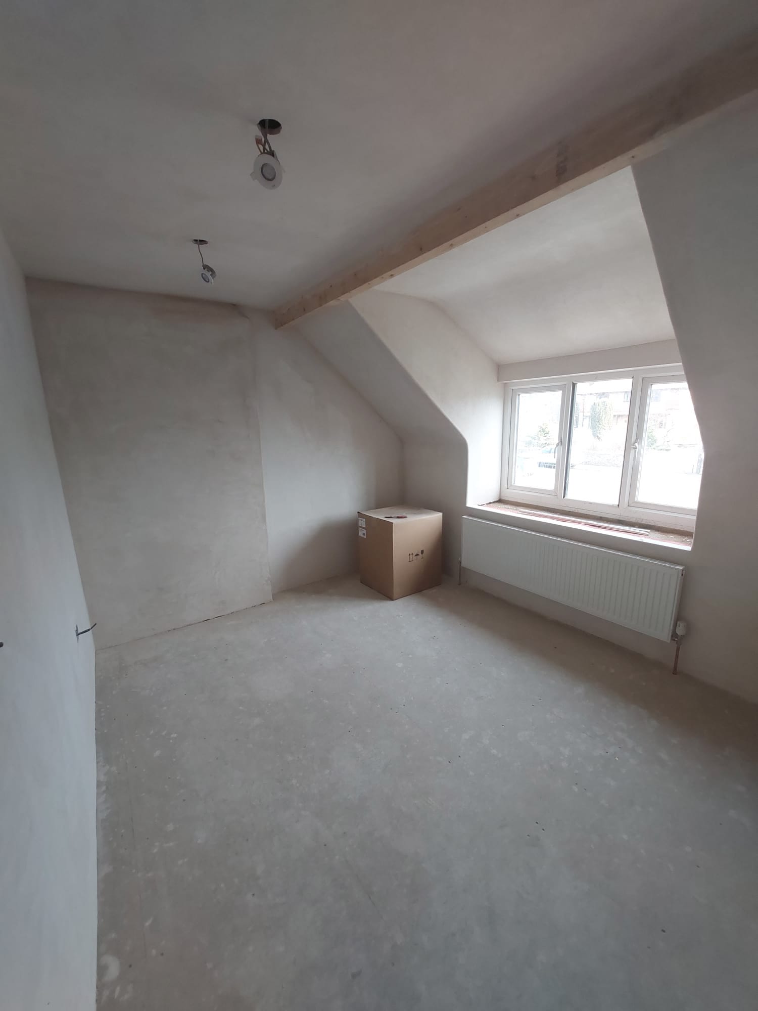 A whole loft room freshly plastered, with dormer window and exposed beam