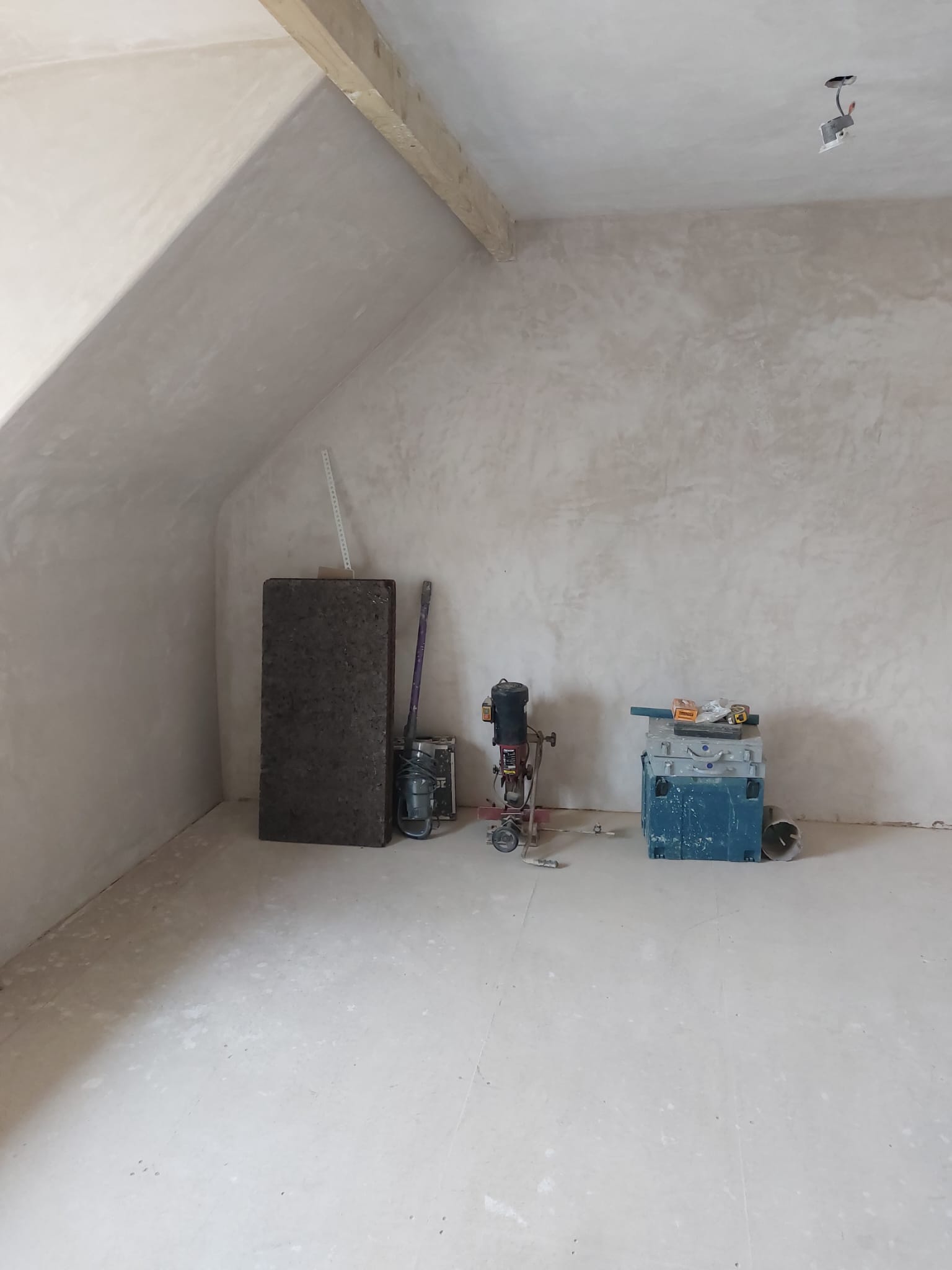Gable wall plastered, with tools set down on the floor