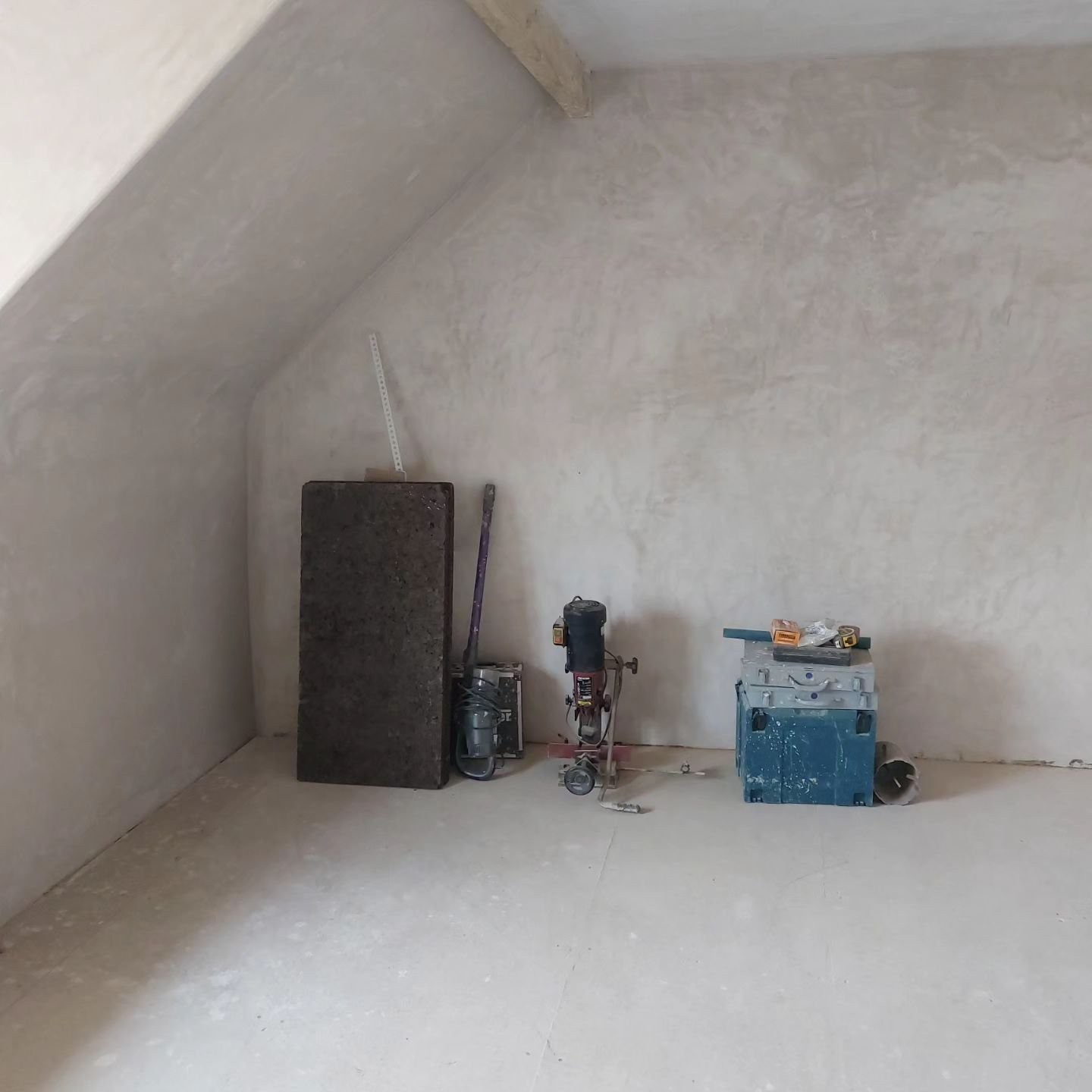 A plastered gable wall in a loft room with tools ready on the floor
